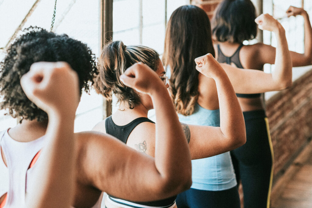 Confident women lifting weights together during a group training session, representing strength, empowerment, and dedication in women’s fitness.